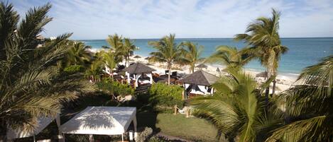 A beach resort with lounge chairs, umbrellas, and a view of the ocean.