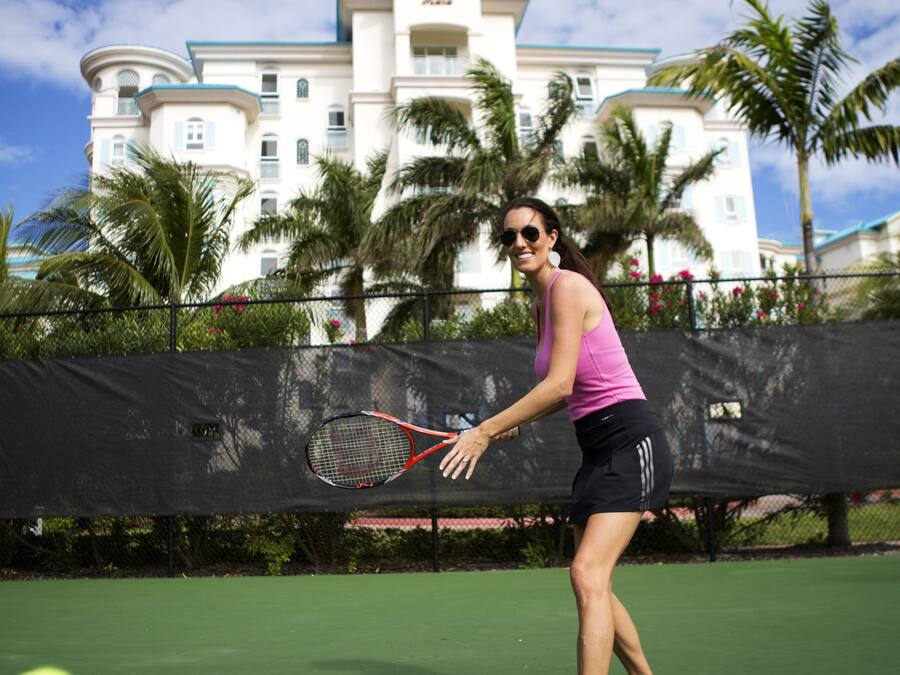 Un campo da tennis con un giocatore in una maglietta rosa e pantaloncini neri, una racchetta da tennis e una palla da tennis.