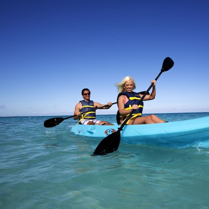 Two people kayaking in a clear blue sea.