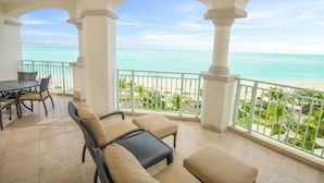 Un balcon avec vue sur la plage, une table à manger et des meubles en osier.