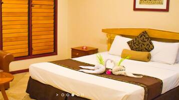 A hotel room with a bed, a brown leather sofa, a small round table, and a window with wooden blinds.