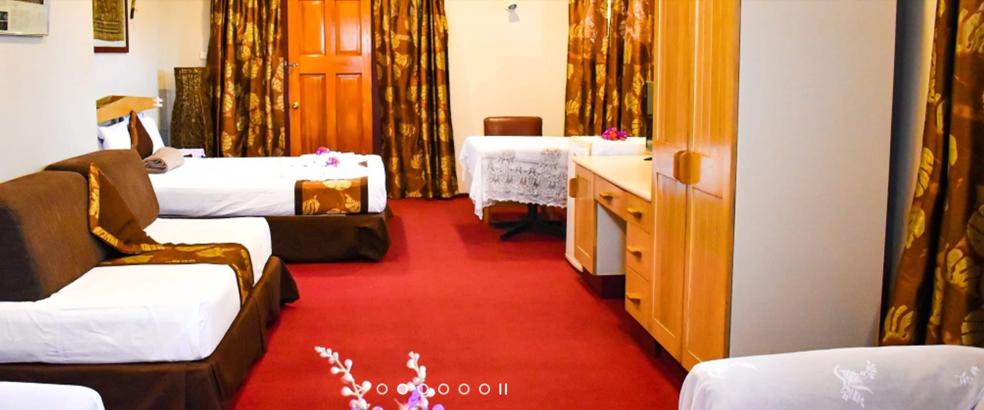 Habitación de hotel con dos camas, un escritorio, una silla y un armario.