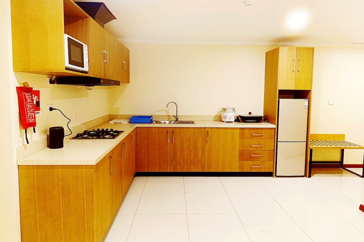 A compact kitchen with wooden cabinets, a microwave, a stove, a sink, and a refrigerator.