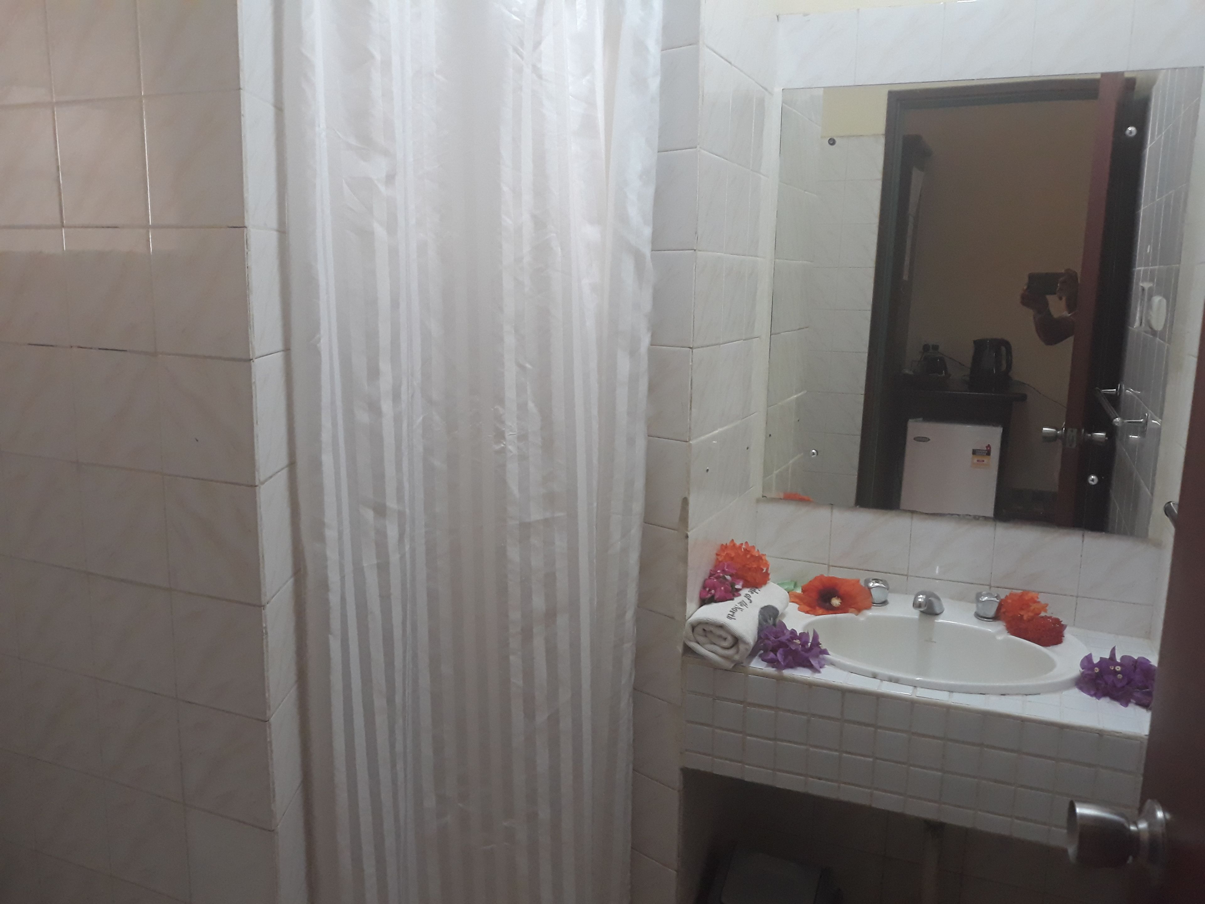 A bathroom with a white sink, mirror, and tiled walls.