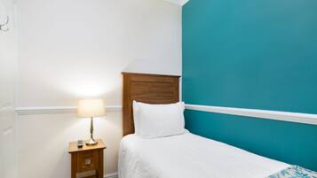 Una cama bien hecha con edredón blanco y una pared de acento color aguamarina.