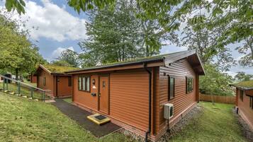 Eine Holzhütte mit Veranda, kleinem Eingang und einem Rasen.