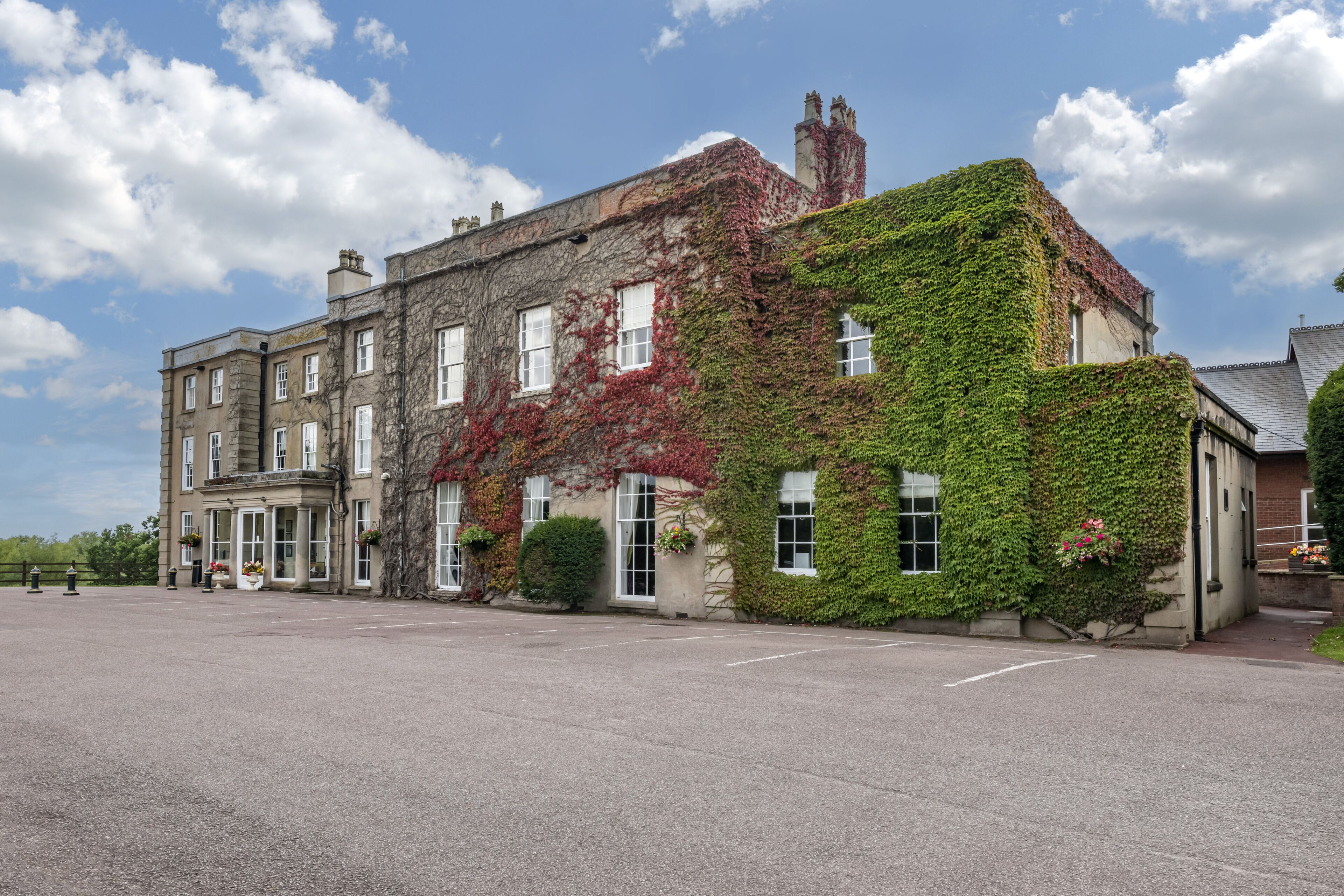 A historic building with ivy-covered walls, large windows, and a spacious courtyard.