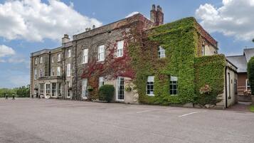 A historic building with ivy-covered walls, large windows, and a spacious courtyard.