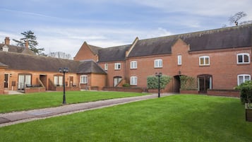 A courtyard with a brick building, a pathway, and a well-maintained lawn.