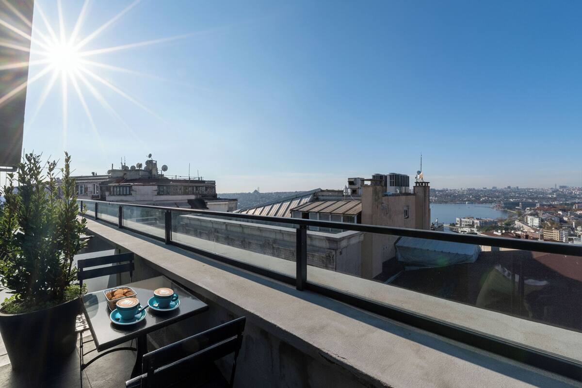 Un balcon avec une table, des chaises et un pot de fleurs.