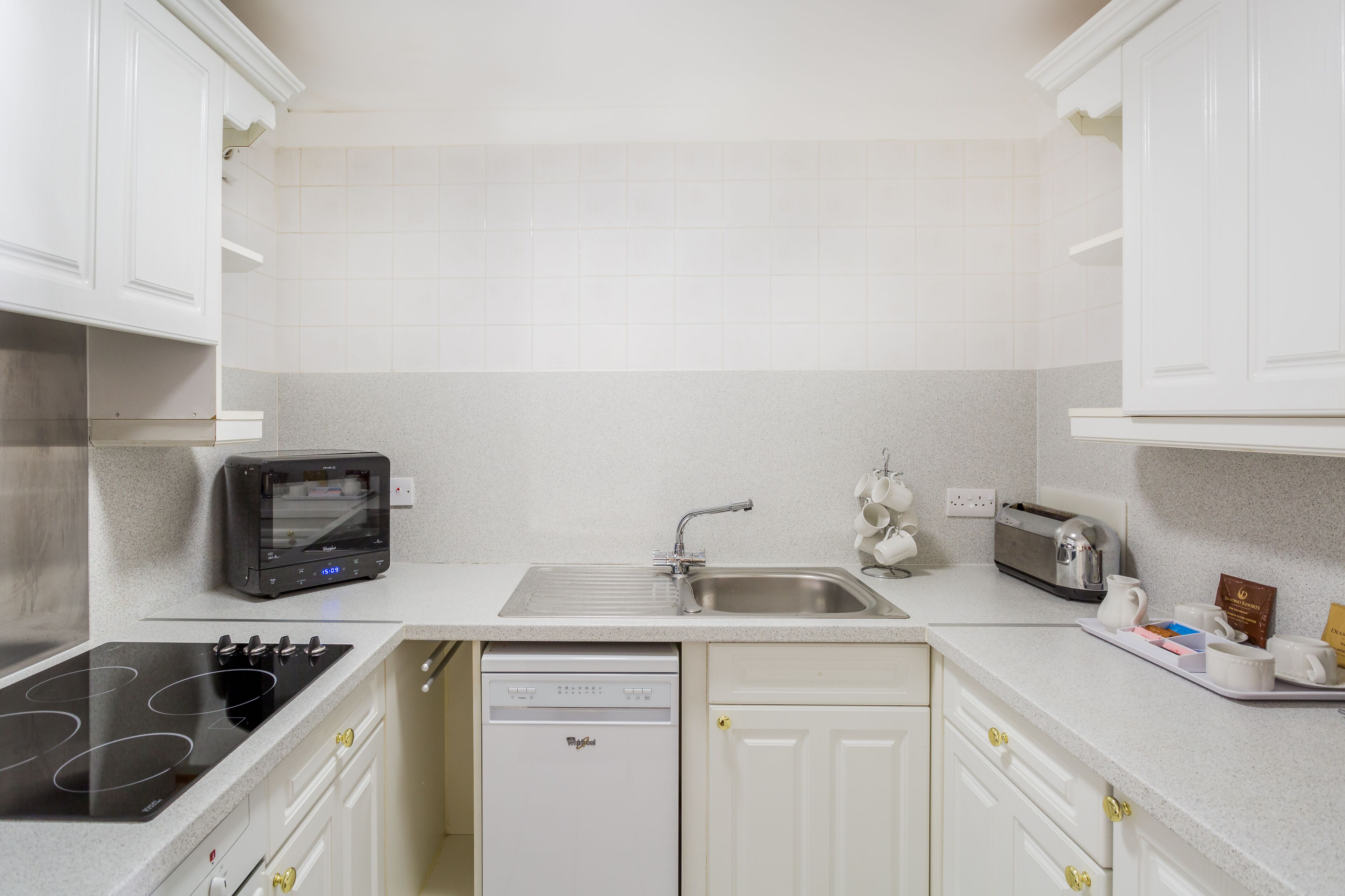 A kitchen with white cabinets, a dishwasher, a toaster, and a microwave.