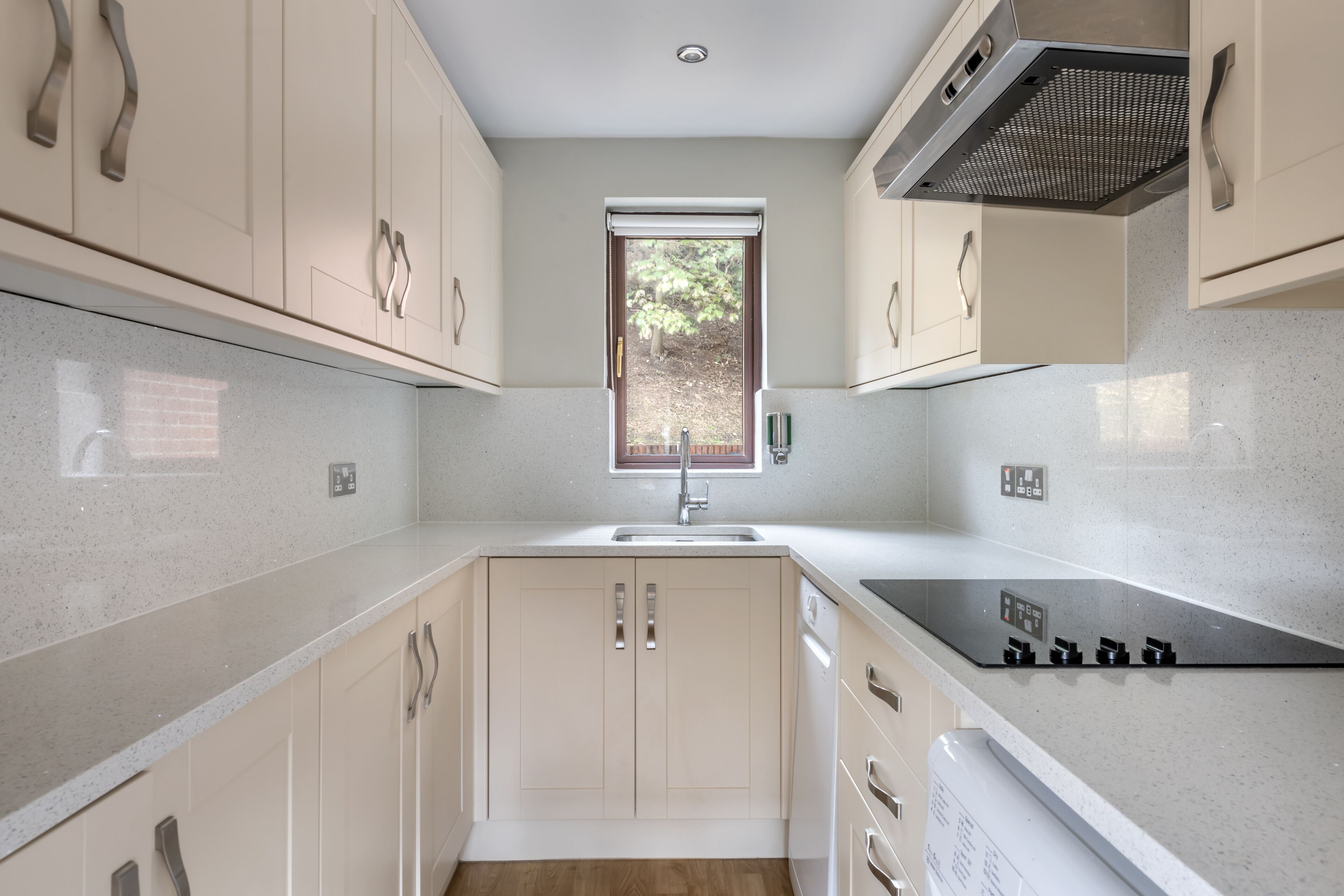 A modern kitchen with a window, stainless steel appliances, and light-colored cabinetry.