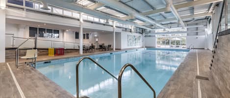 Una piscina interior con una vista despejada del área de la piscina, incluyendo los asientos junto a la piscina y el borde de la misma.
