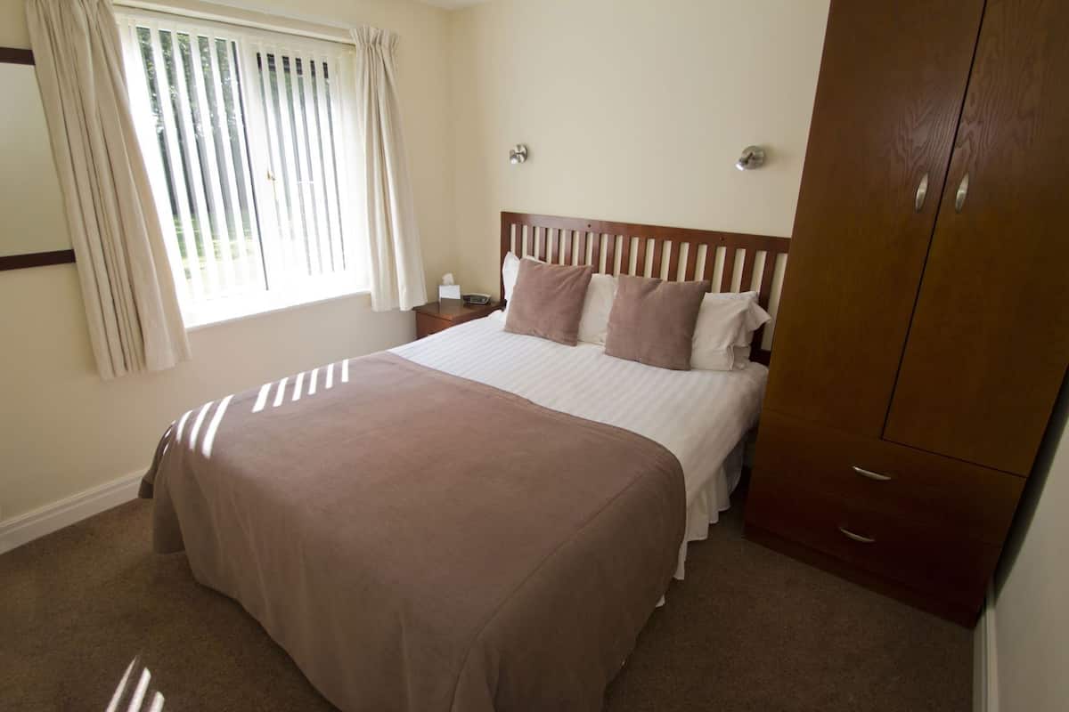 A bedroom with a bed, bedside table, and a wardrobe.