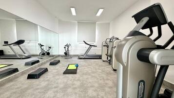 Une salle de sport équipée de tapis de course, de vélos elliptiques et d’appareils de musculation.