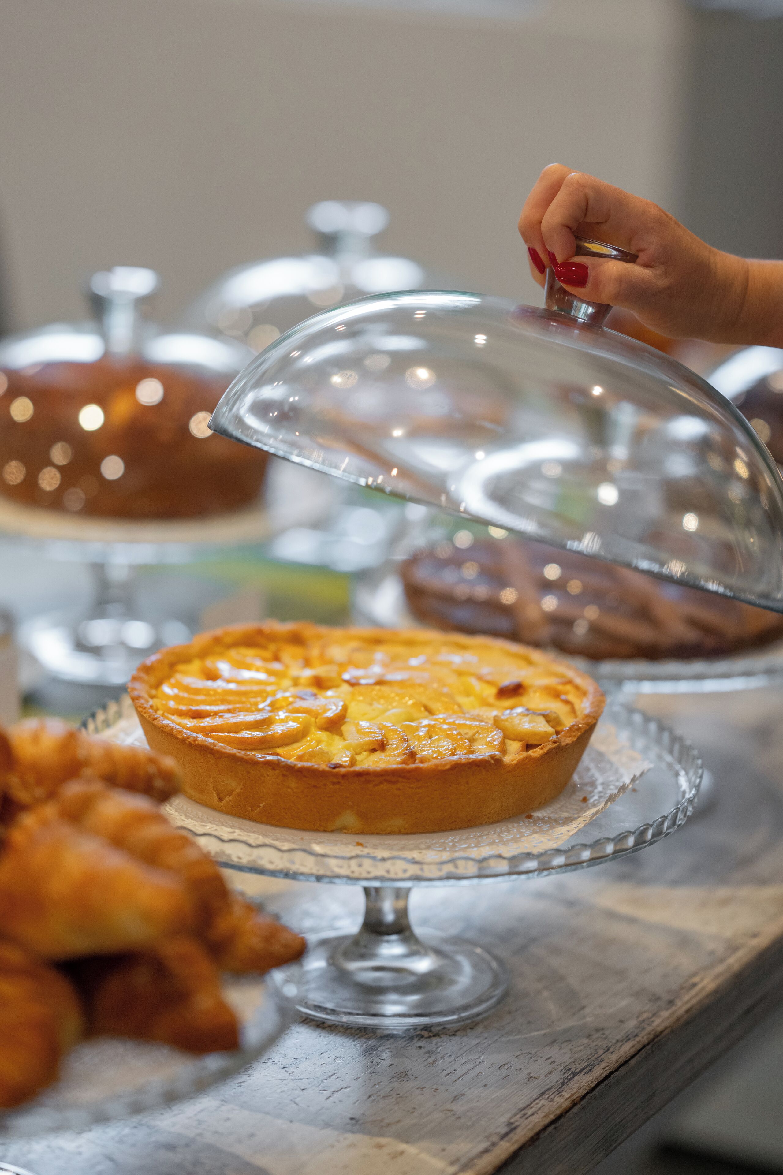 A dessert display with a covered tart and pastries.