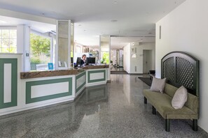Un espace d’accueil comprenant un comptoir de réception, un canapé et un banc.