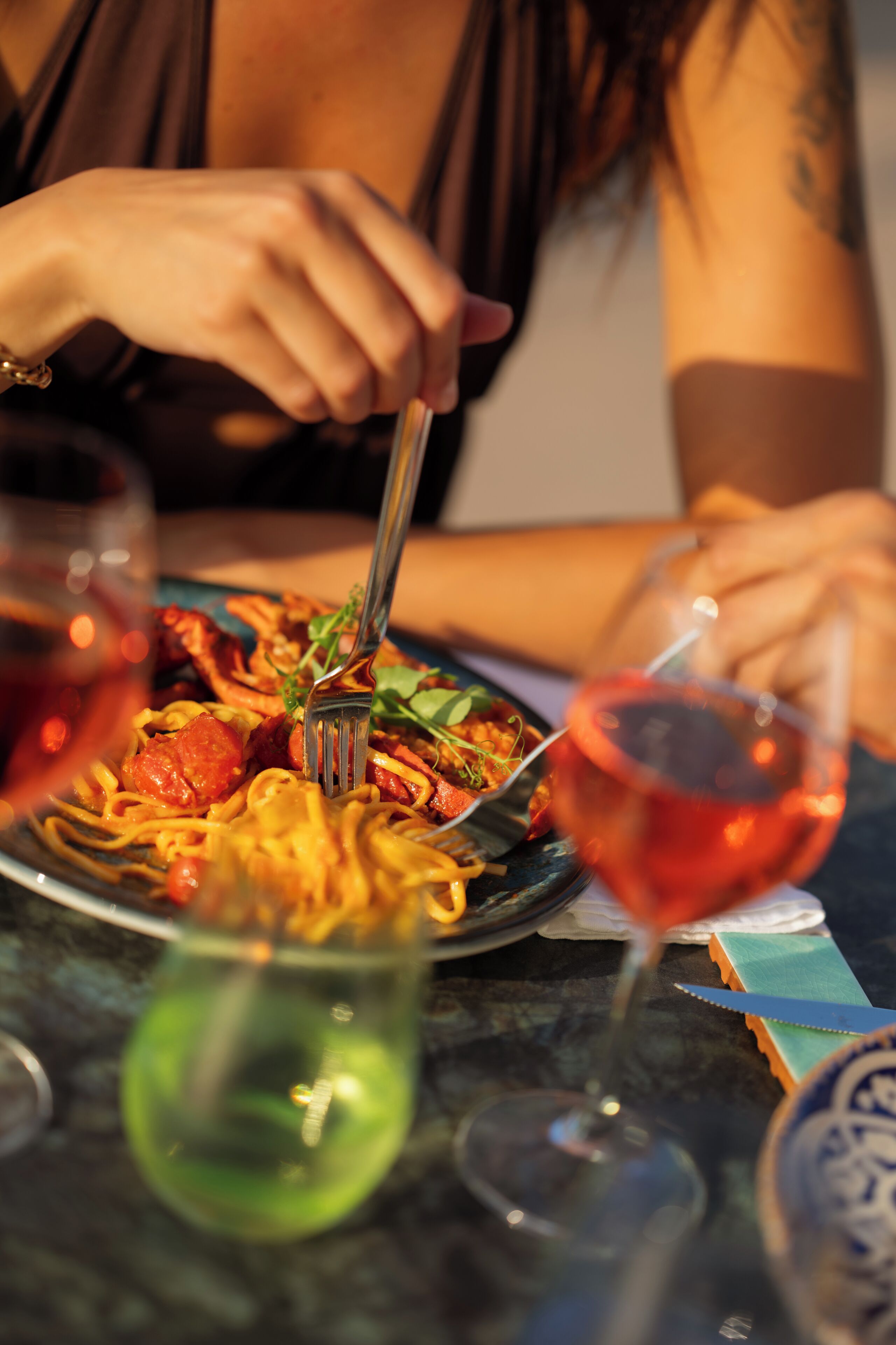 Una mesa de comedor con un plato de espagueti y una copa de vino tinto.