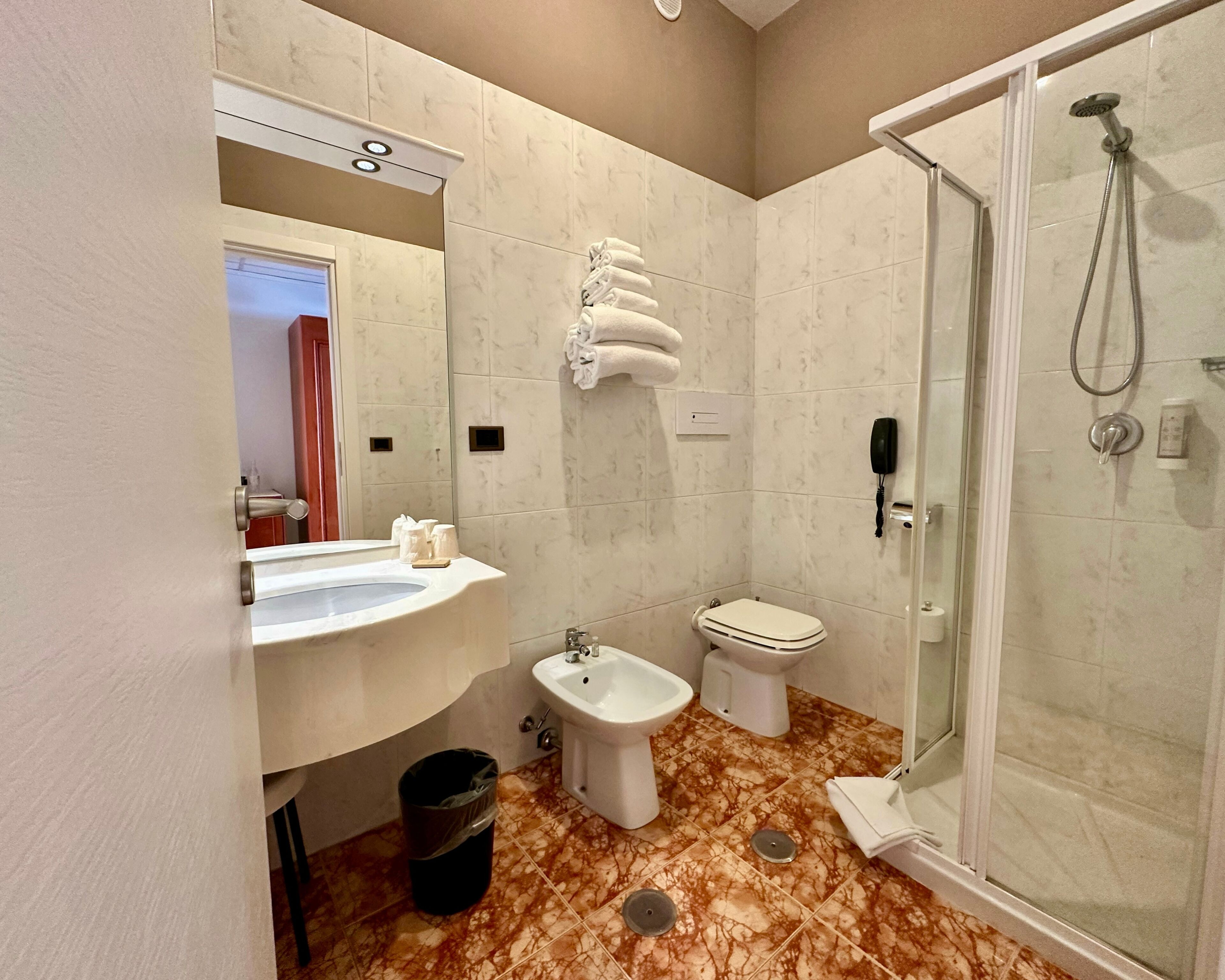A bathroom with a sink, bidet, toilet, and a glass-enclosed shower.