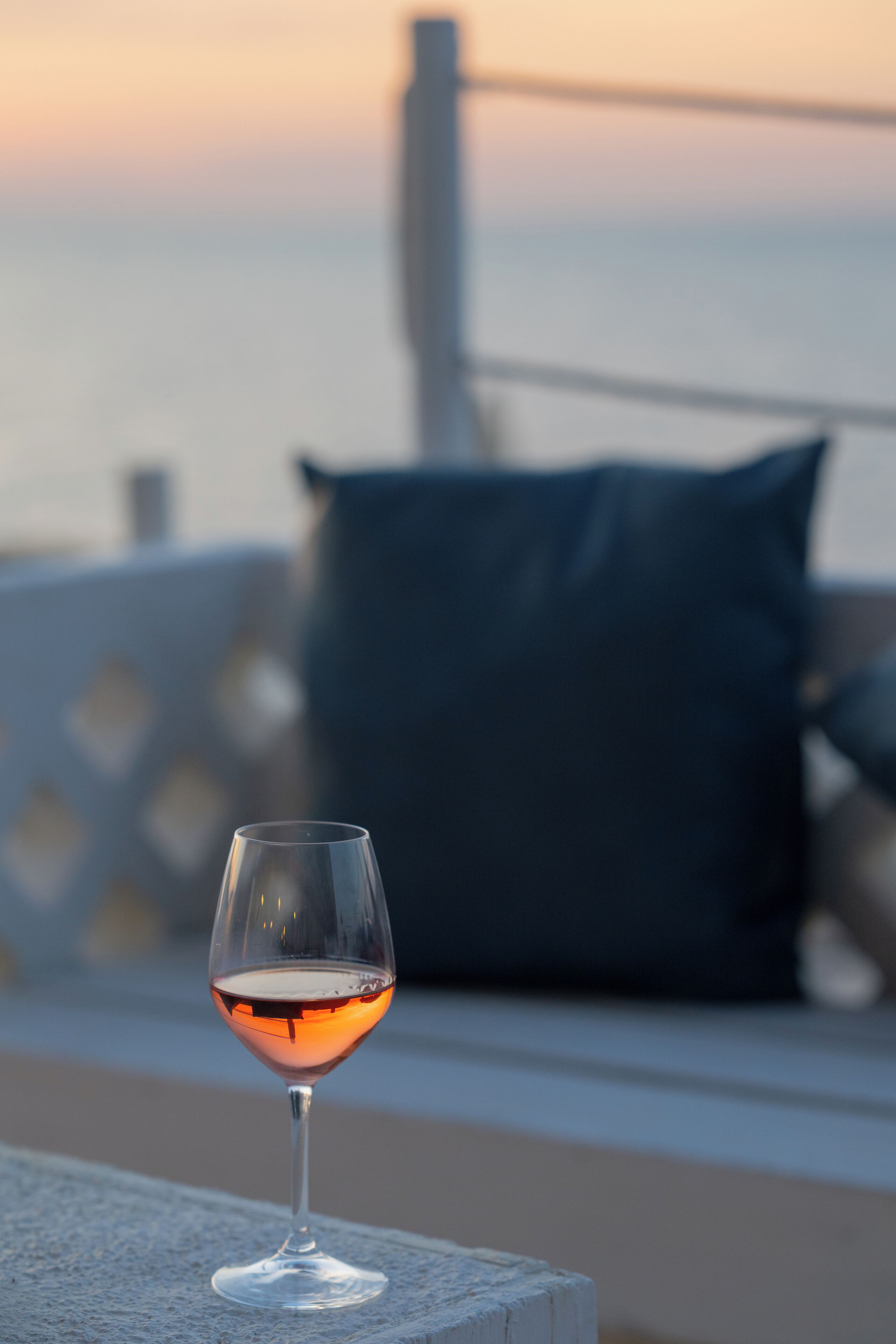 Ein Glas Rotwein auf einem Balkon mit Meerblick und einer Brüstung.