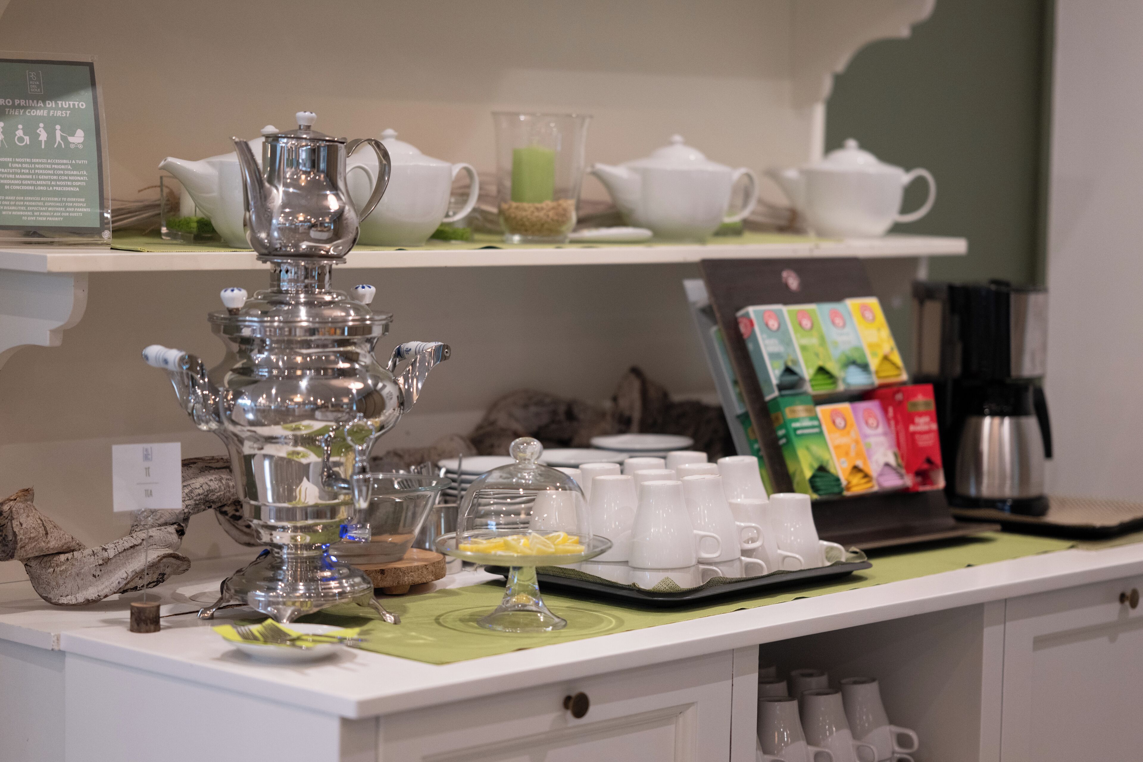 Un buffet de petit-déjeuner proposant une variété de thés et de cafés, une théière en argent décorative et une présentation de produits emballés.