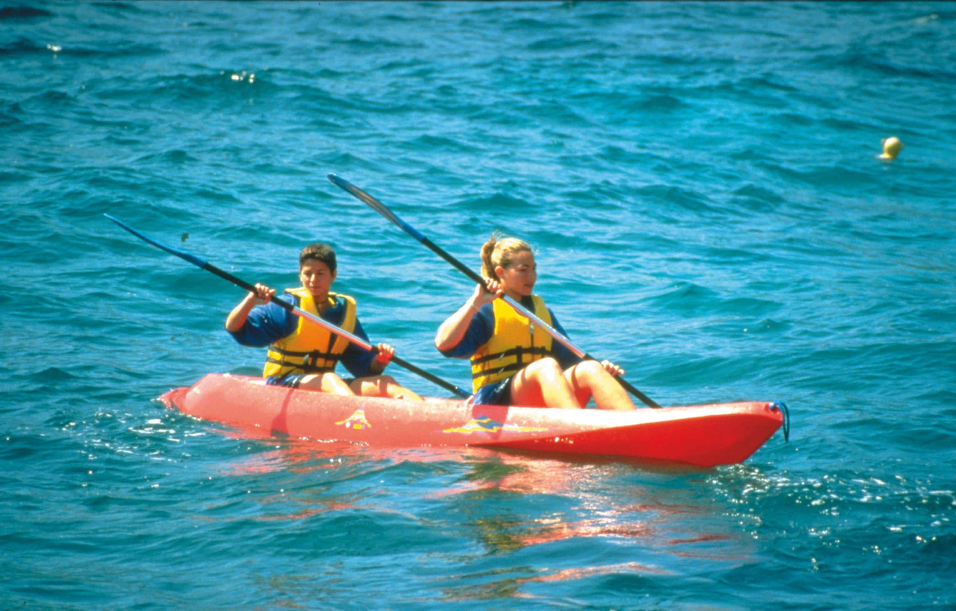 Two people in a red kayak on a body of water.