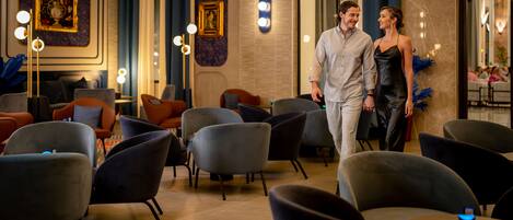 Un vestíbulo de hotel moderno con muebles contemporáneos, una pared de mármol e iluminación decorativa.