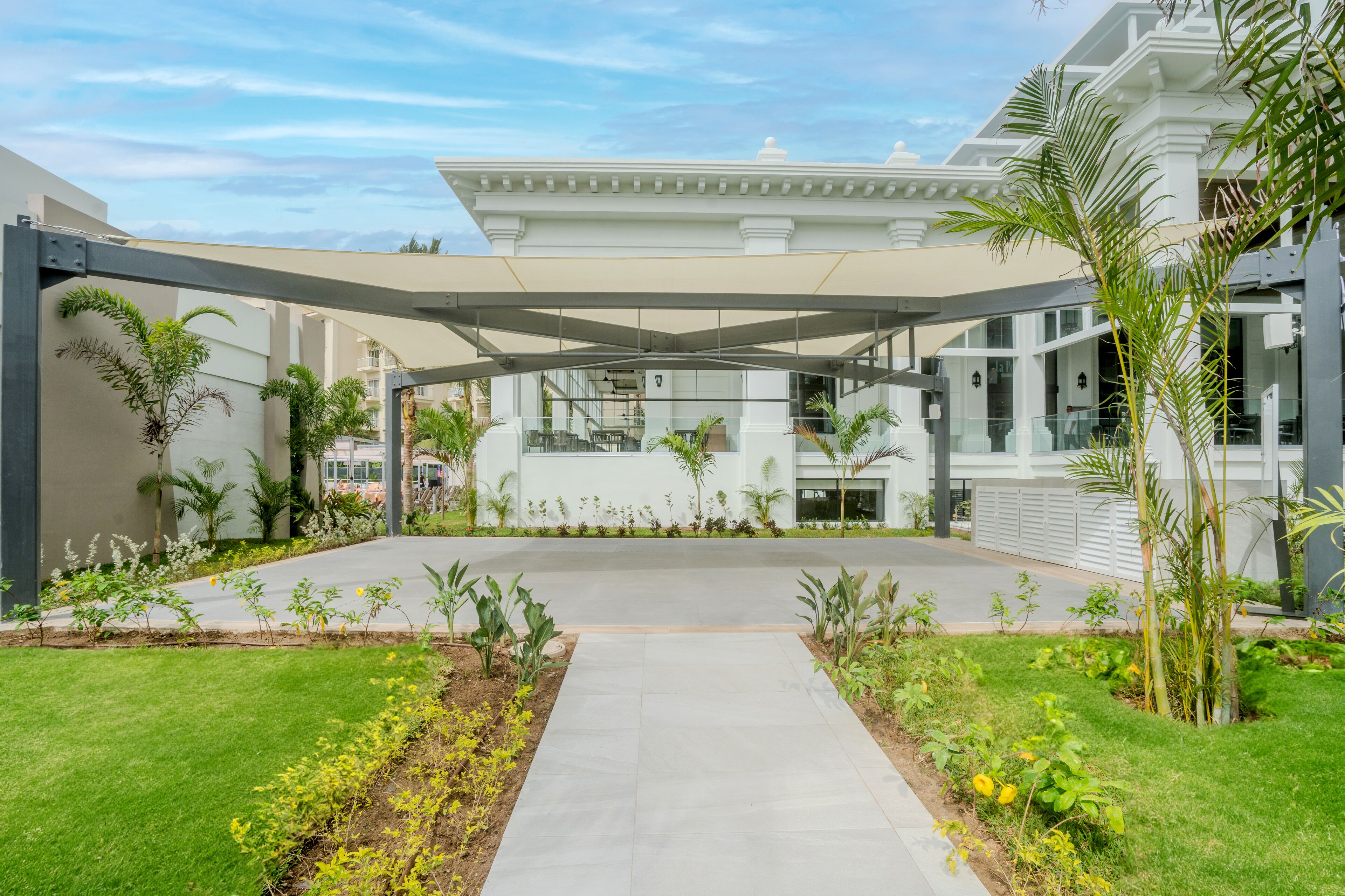 Un edificio moderno con vestíbulo cubierto, un patio central y abundante vegetación.