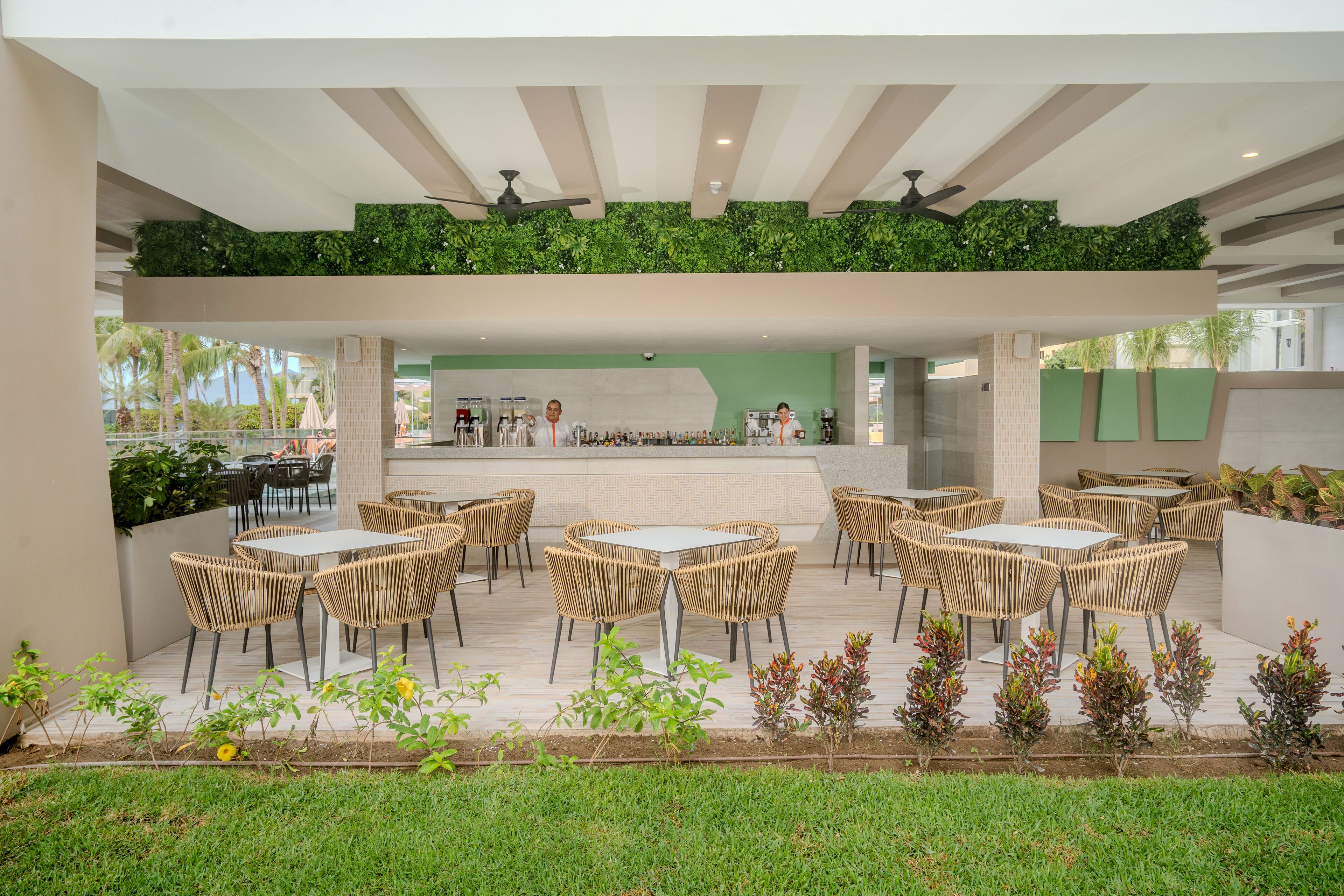 Un'area patio esterna con mobili in vimini, un bar e un muro verde.