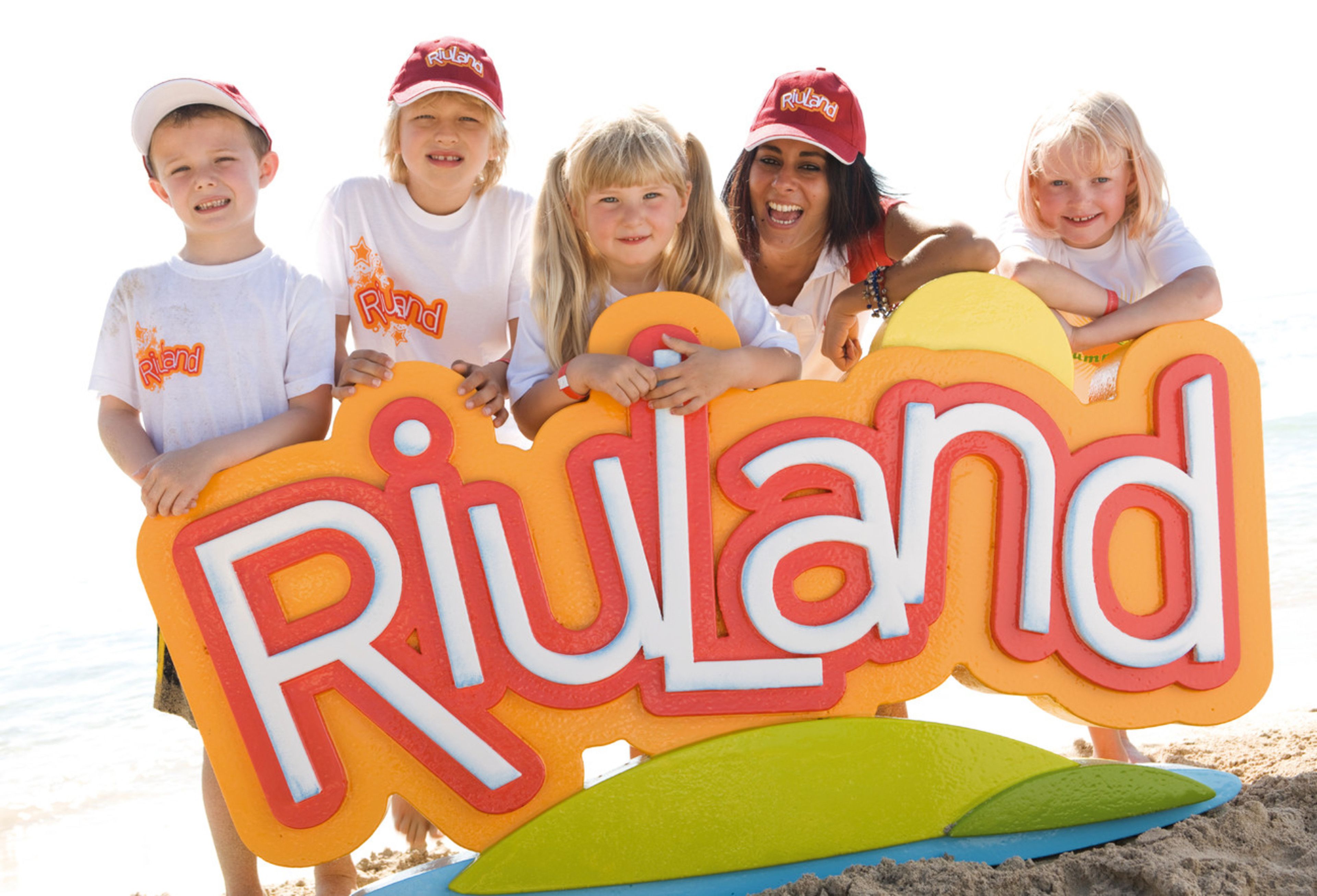 A group of people holding a sign that reads "Riuland" on a beach.