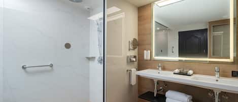 A modern bathroom with a glass-enclosed shower, a large mirror, and a double sink vanity.