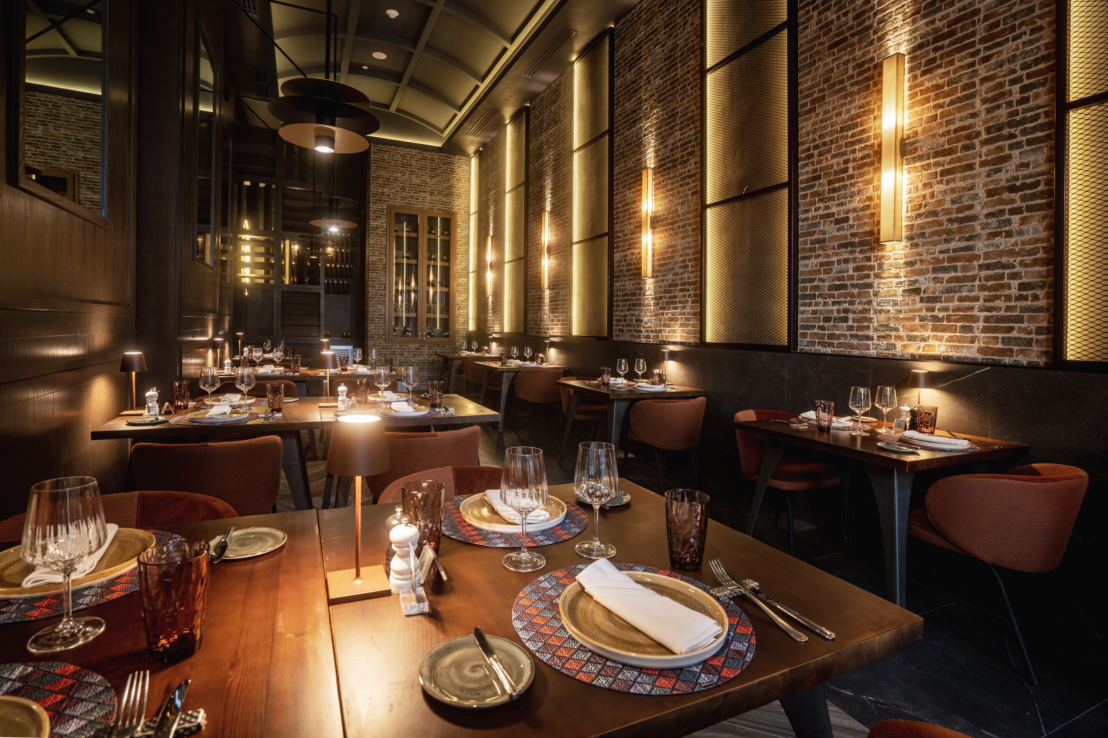 Un restaurant avec des tables en bois, des chaises en métal et des murs en briques.