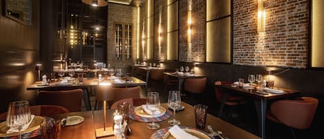 A restaurant with wooden tables, metal chairs, and brick walls.