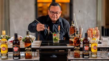 A bartender preparing a drink with various bottles of Havana Club rum and other liquors on a bar counter.
