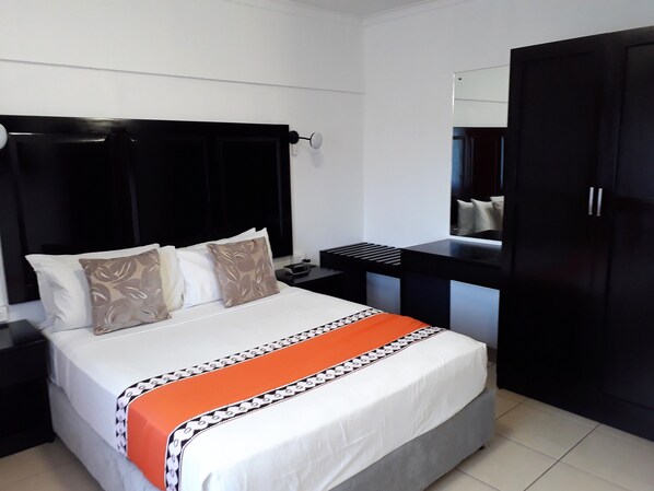 A hotel room with a bed, a desk, and a wardrobe.