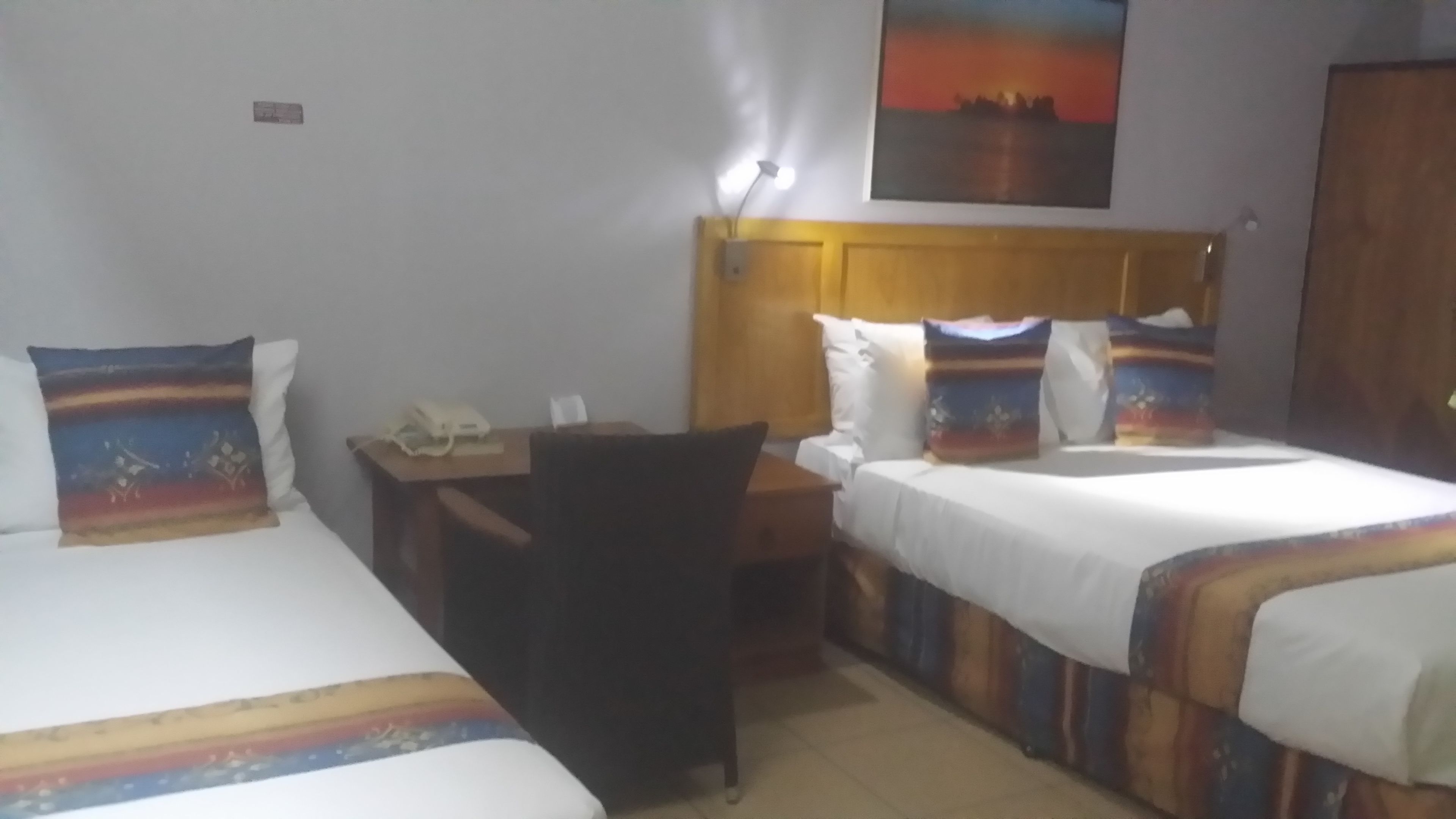 A hotel room with two beds, a desk, and a chair.
