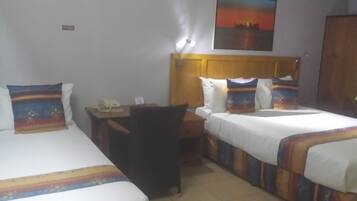 A hotel room with two beds, a desk, and a chair.