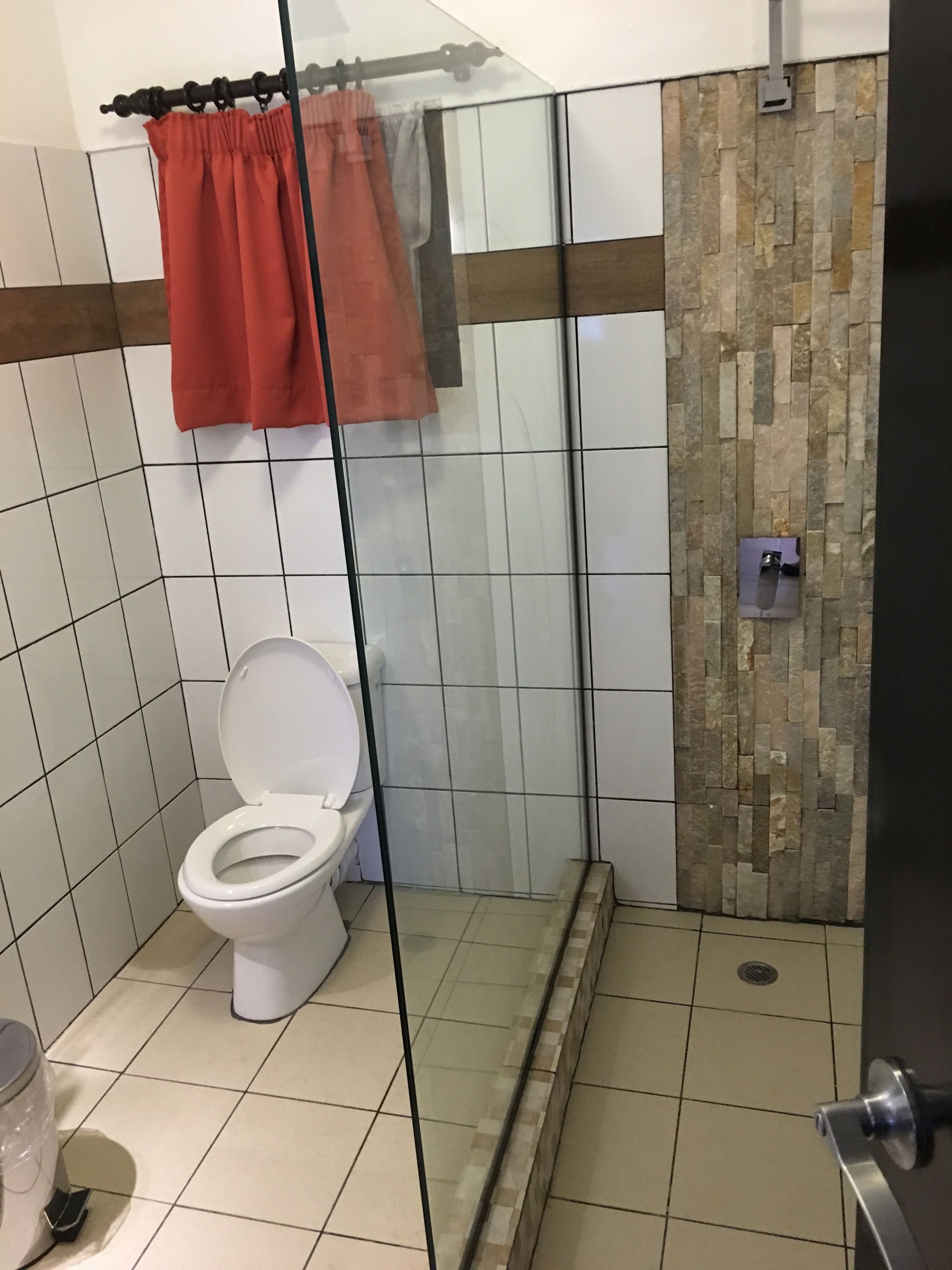 A bathroom with a toilet, a shower area, and a tiled floor.