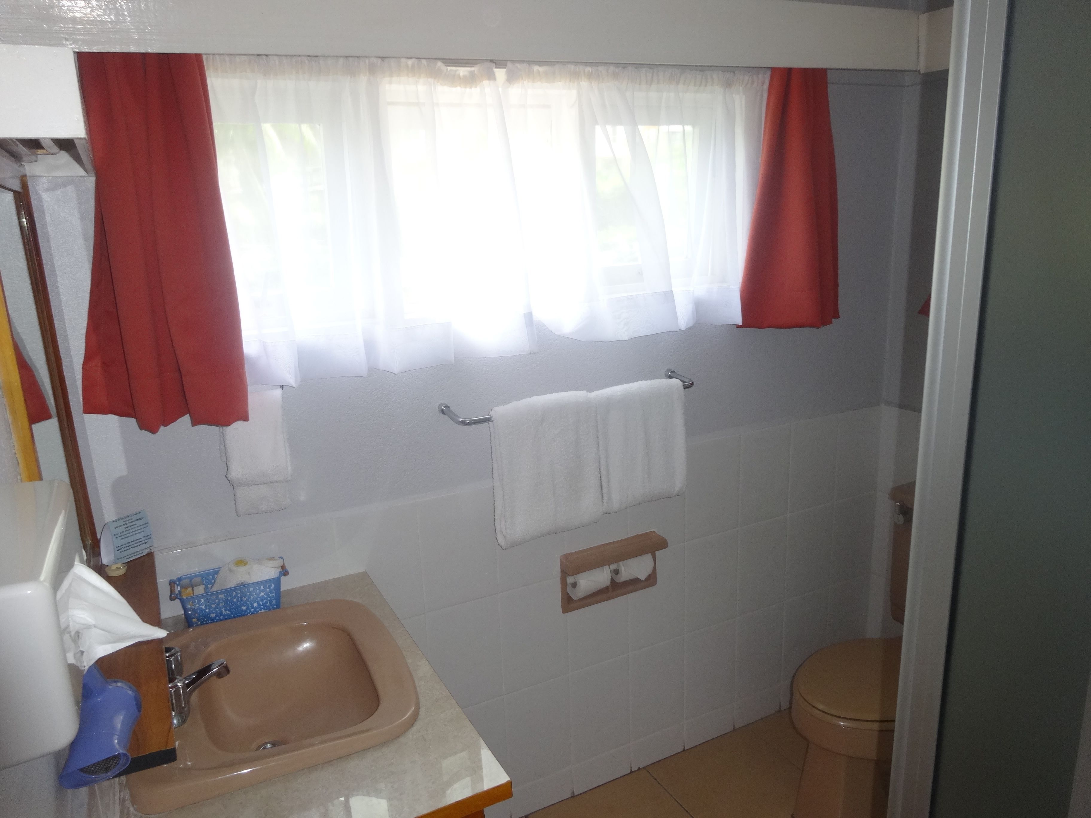 Un baño con lavamanos, espejo, toallero y retrete.