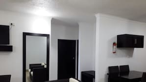 A modern living room with a sofa, a dining table with chairs, a flat-screen TV mounted on the wall, and a black cabinet. - Suva Motor Inn (Suva)