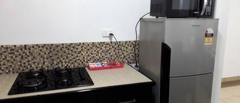 Una cocina con estufa a gas, microondas y refrigerador.
