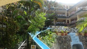 A multi-level outdoor area with a water slide, lush greenery, and a stone wall. - Suva Motor Inn (Suva)
