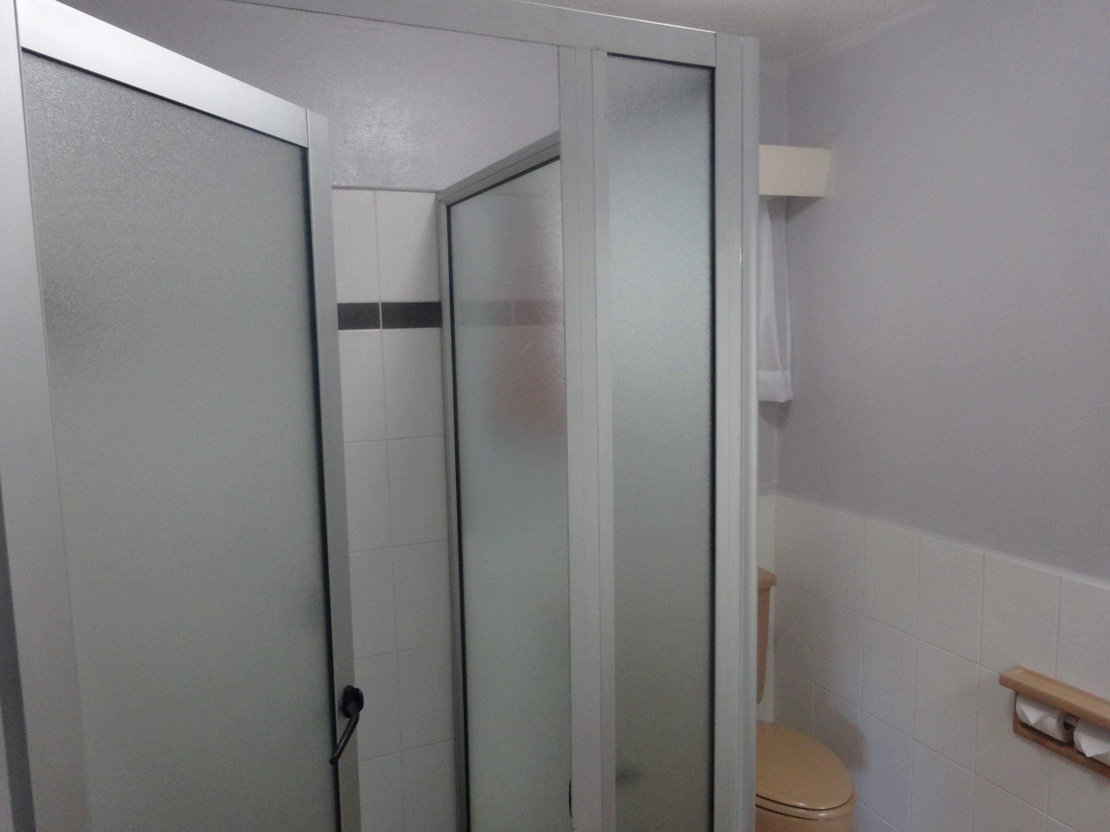 Une salle de bain avec une douche à parois de verre, des toilettes et un porte-serviettes.