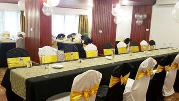 Un salón de conferencias con una larga mesa, sillas adornadas con cintas amarillas y globos.