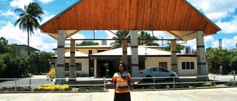 A woman standing in front of a building with a wooden roof and concrete pillars.