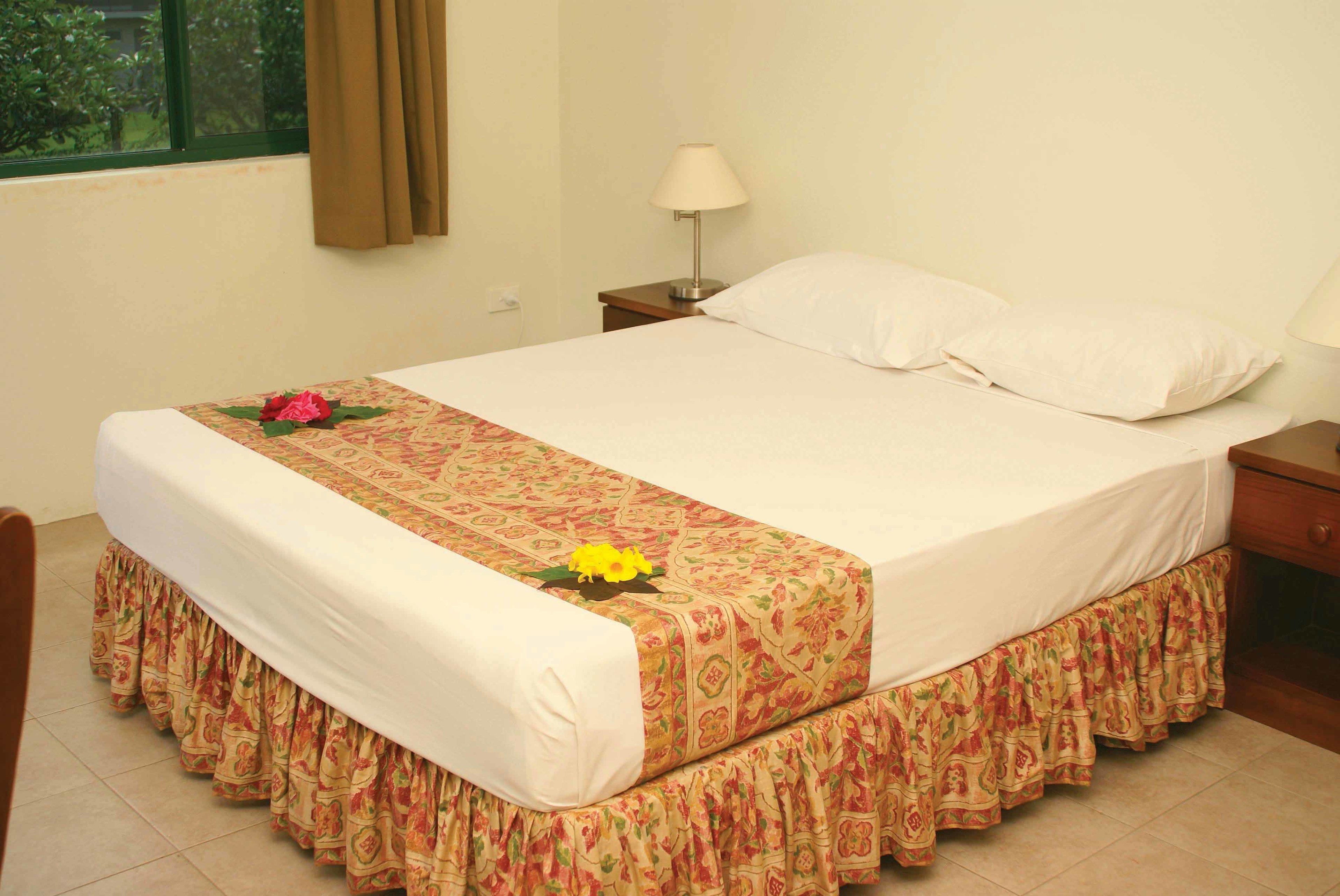 A neatly made bed with a floral bedspread and a decorative pillow.