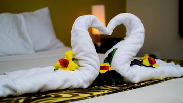 Una cama con sábanas blancas y una disposición decorativa de toallas en forma de corazón.