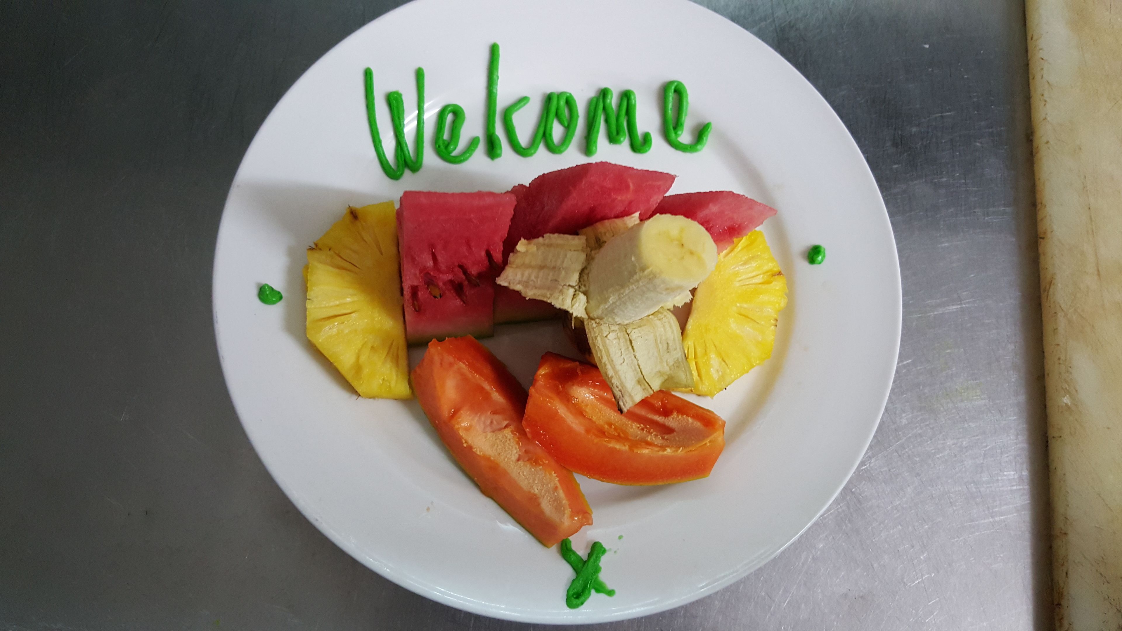 Um prato com frutas fatiadas e uma mensagem de 'Bem-vindo'.