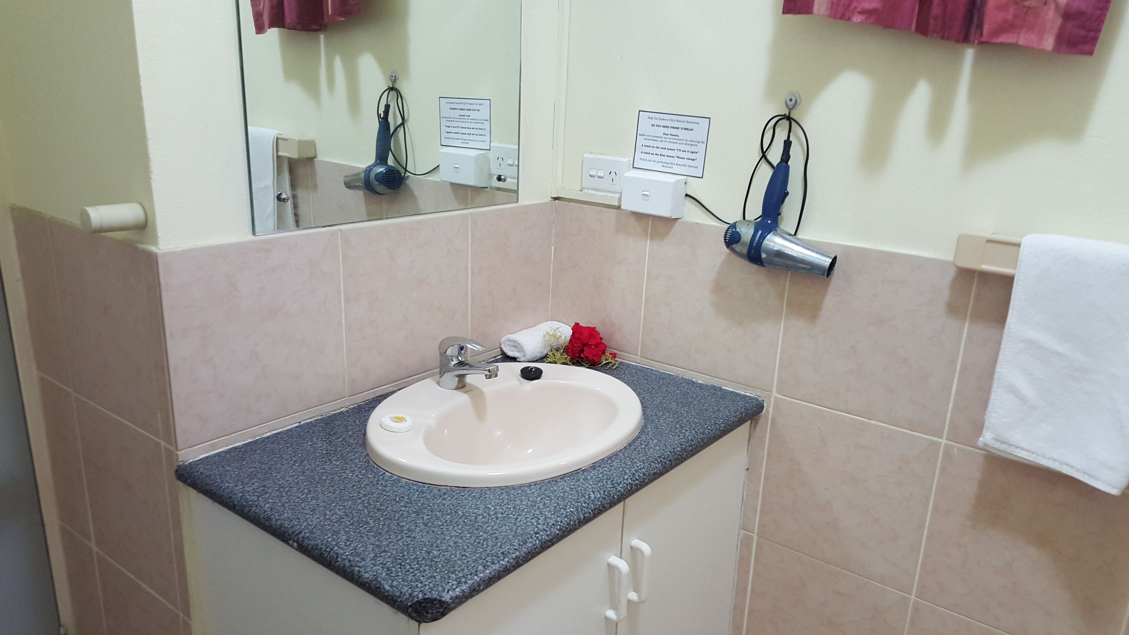 A bathroom with a sink, mirror, towel rack, and a hairdryer.