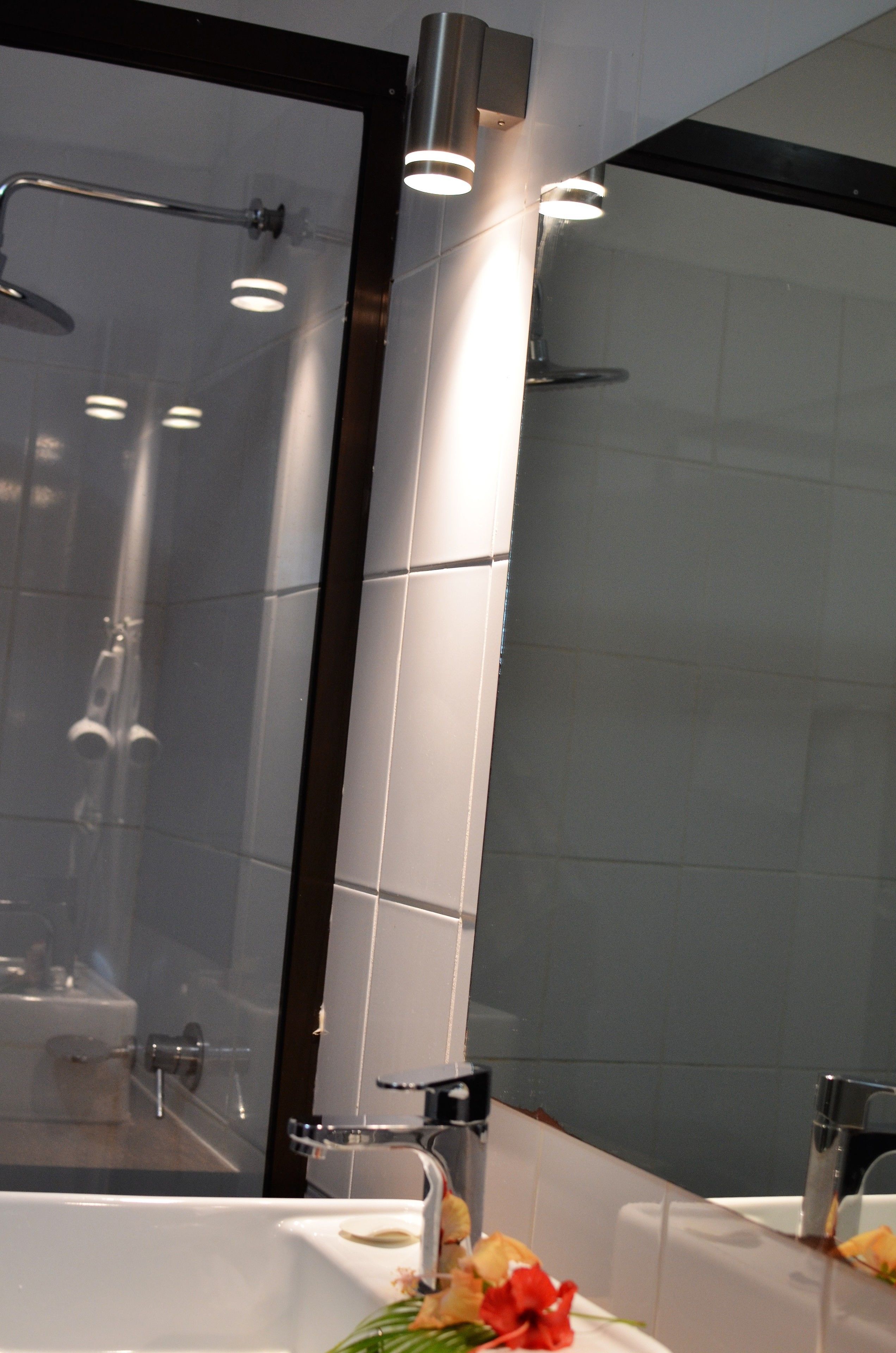Une salle de bain moderne avec une douche à parois de verre, un lavabo blanc et un miroir.